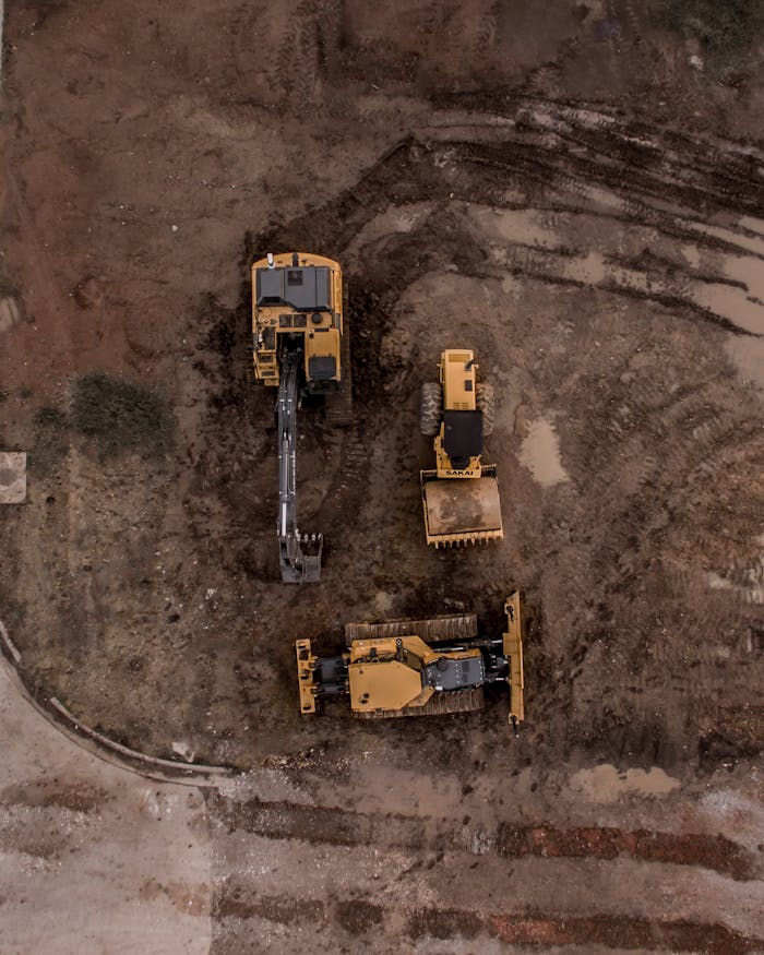 pexels-photo-1579356 An aerial shot of heavy machinery at a construction site, including excavators and road rollers.